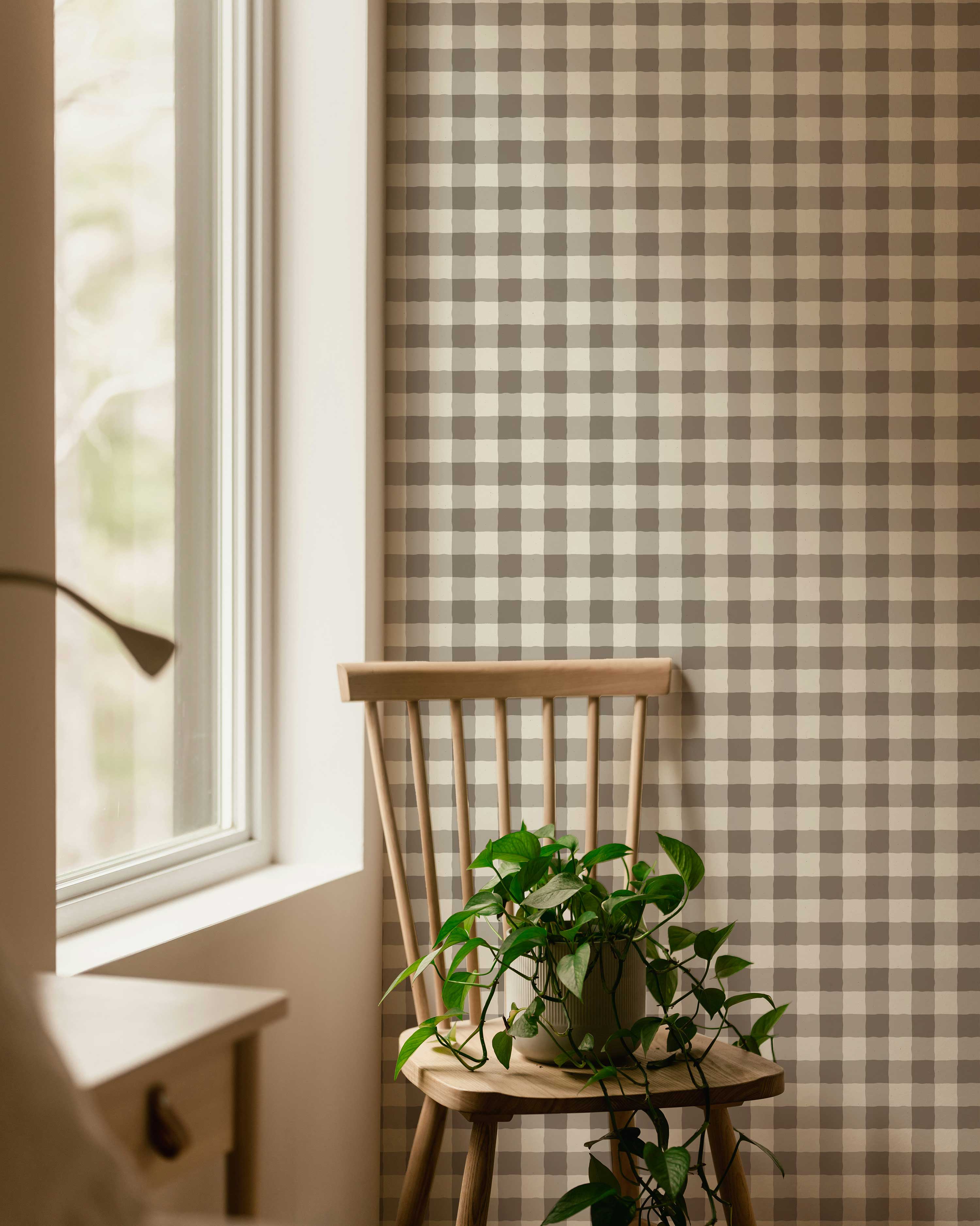 Wooden chair with a plant against a plaid wall