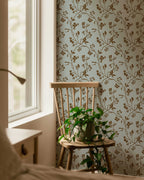 Floral wallpaper with a wooden chair and plant in a room with natural light.