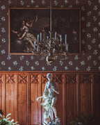 Decorative interior with wallpaper and a statue, potted plants, and wall art in a room with wooden paneling.