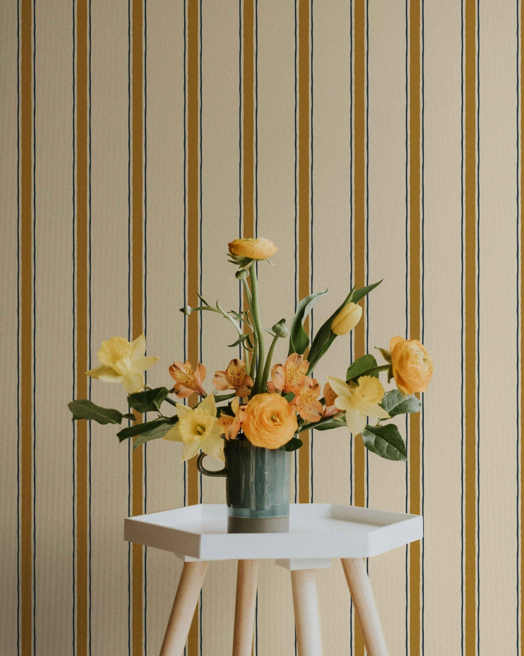 Hexagonal white table with a vase of flowers against a striped wall.